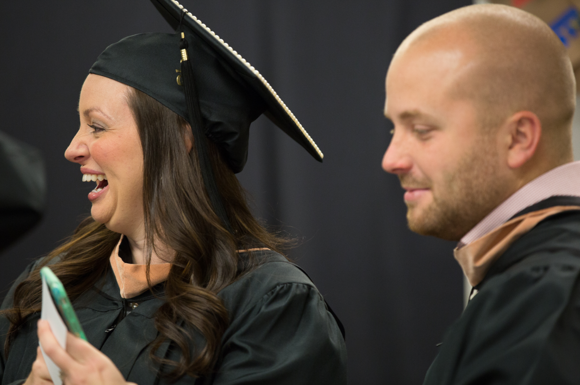 Two people in graduation attire smiling