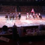 Two groups of horse riders within an indoor arena