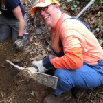 Woman wearing an orange shirt and holding a pickaxe
