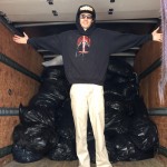 A person posing in front of a stack of black bags inside of a truck trailer