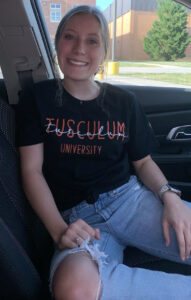 Girl in Tusculum Shirt Smiling in a Car