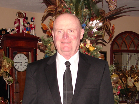 Smiling Bald Man in a Suit in front of a Christmas Tree