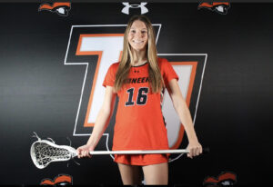 Young woman in a sports jersey posing with a lacrosse stick