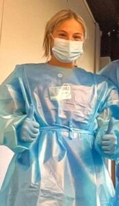 Young woman in medical safety gear posing with two thumbs up