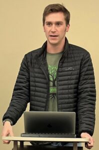 Young man speaking at a podium with a laptop in front of him